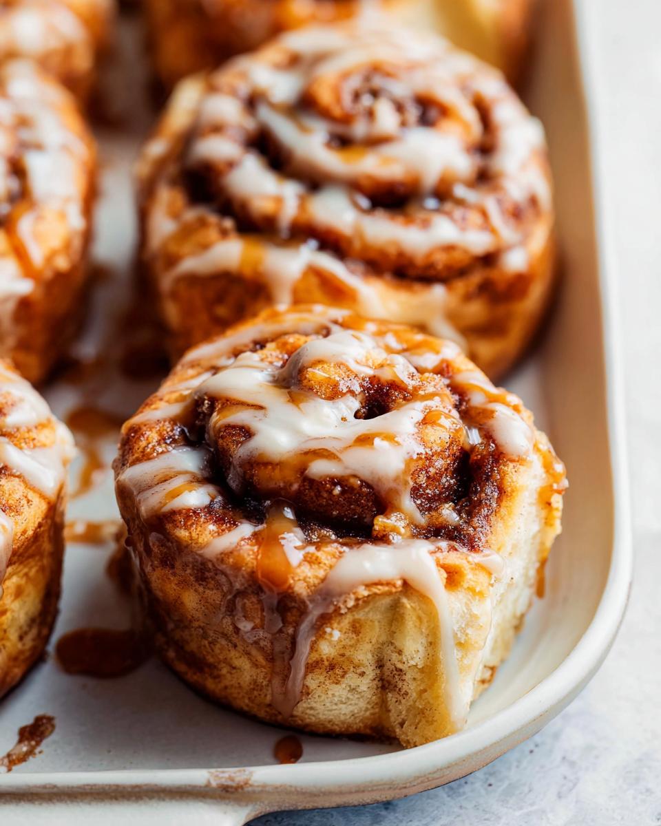 Close-up of freshly baked Cinnabon caramel recipe rolls, drizzled with icing and caramel sauce.