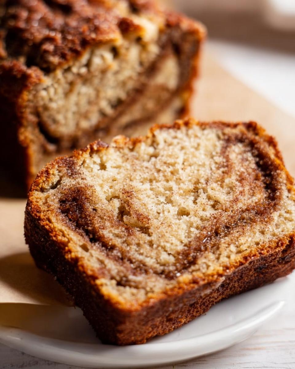 A close-up of a moist slice of Cinnamon Swirl Banana Bread showing the rich brown cinnamon swirl pattern.