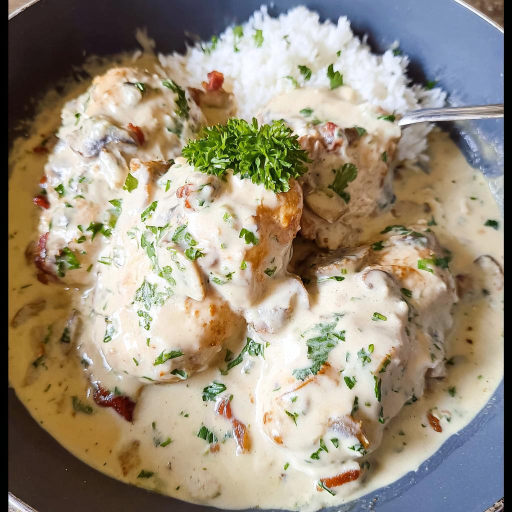 Close-up of Creamy Smothered Chicken and Rice covered in a rich sauce with mushrooms and parsley.