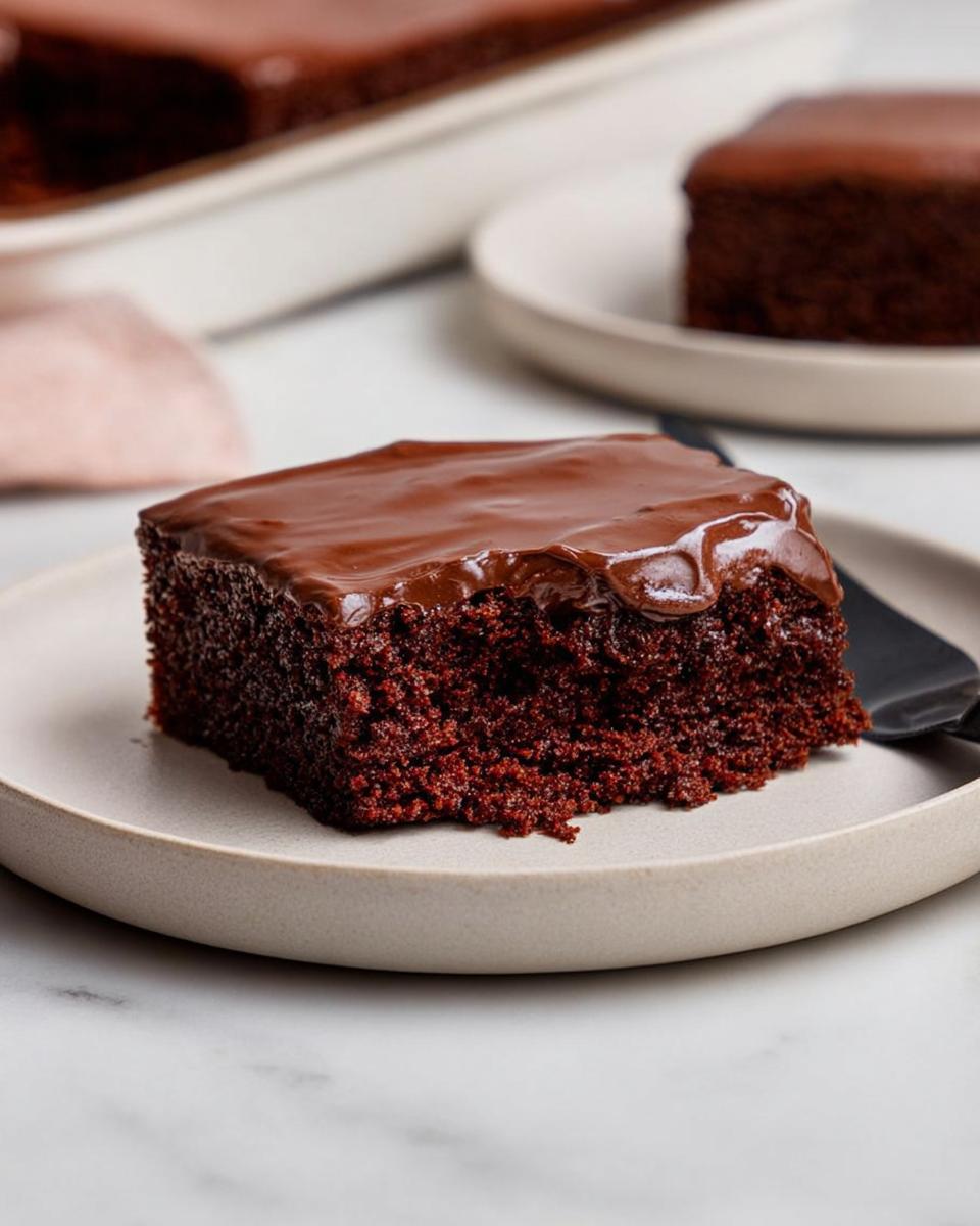A square slice of rich, dark chocolate Easy Snacking Sheet Cake topped with glossy chocolate ganache.