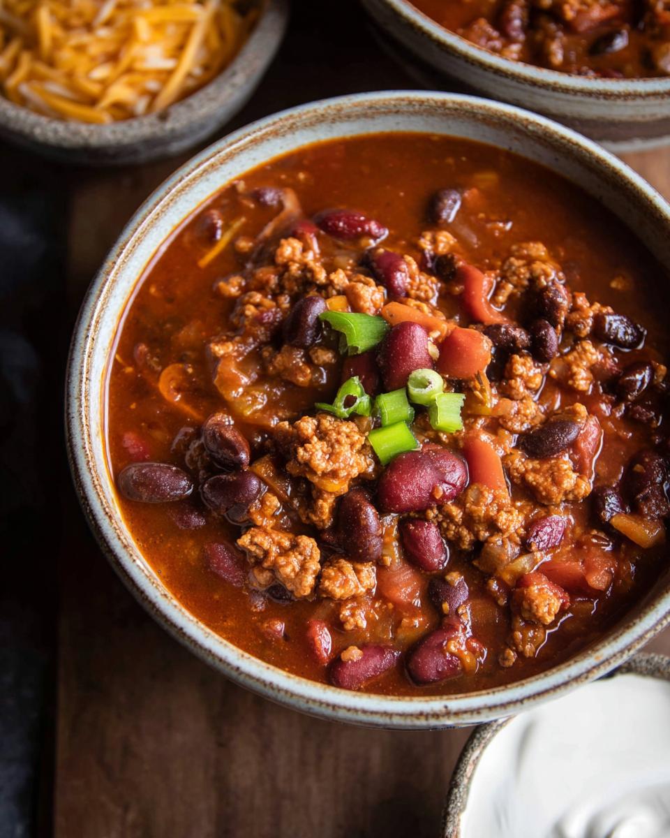 A close-up of a bowl of delicious Ground Turkey Chili (Stovetop) topped with chopped green onions.