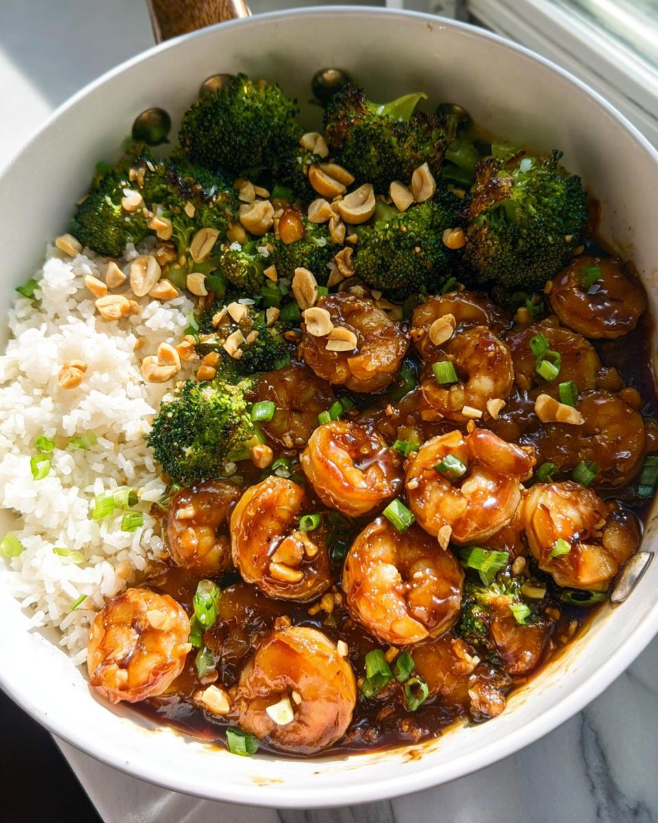A close-up of Honey Garlic Shrimp Bowls featuring glossy shrimp, roasted broccoli, and white rice, topped with peanuts and green onions.