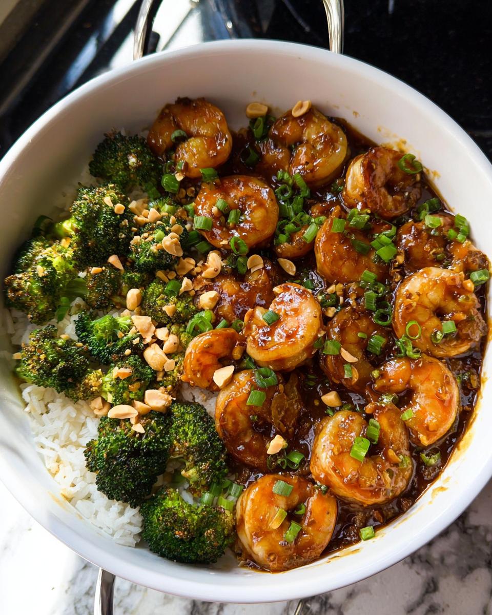 A close-up of Honey Garlic Shrimp Bowls, featuring glazed shrimp, steamed broccoli, and white rice, topped with chopped peanuts and green onions.
