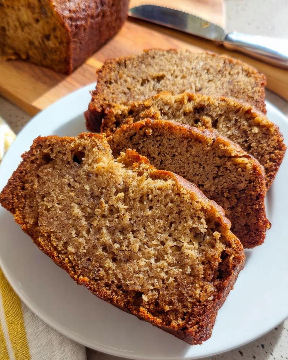 Close-up of three thick slices of moist One Bowl Banana Bread served on a white plate.