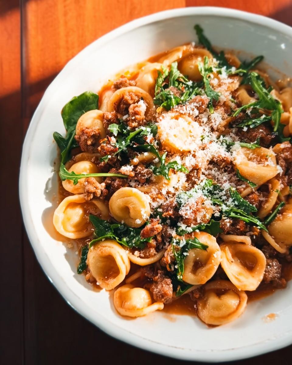 Close-up of a bowl of one pan pasta with crumbled sausage, arugula, and grated cheese. A popular dinner idea recipe.