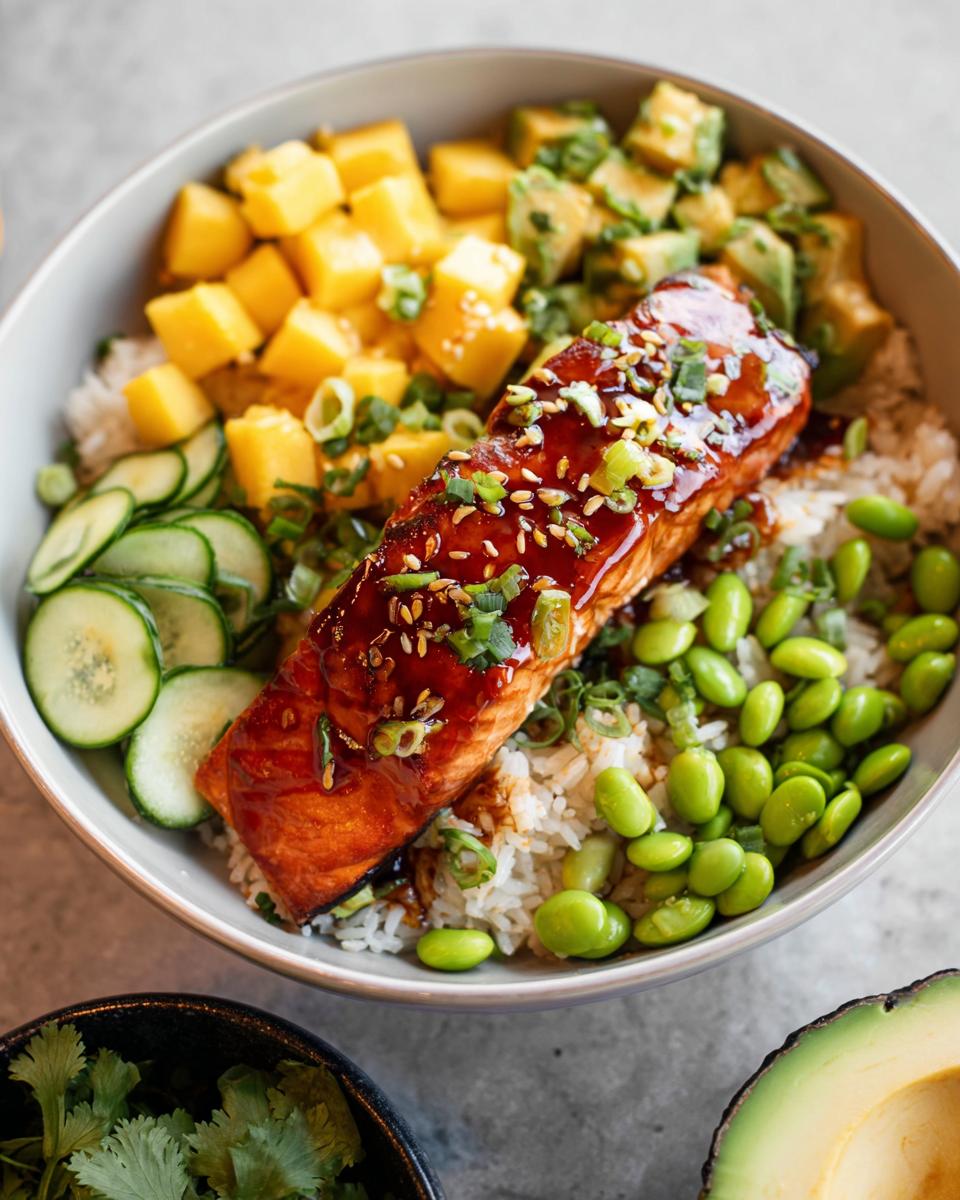 A vibrant Salmon Bowl with glazed salmon, rice, mango, avocado, edamame, and cucumber.
