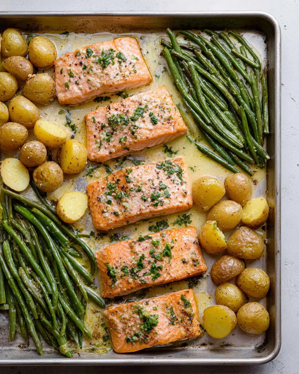 Overhead view of a sheet-pan salmon and veggies meal with roasted potatoes and green beans.