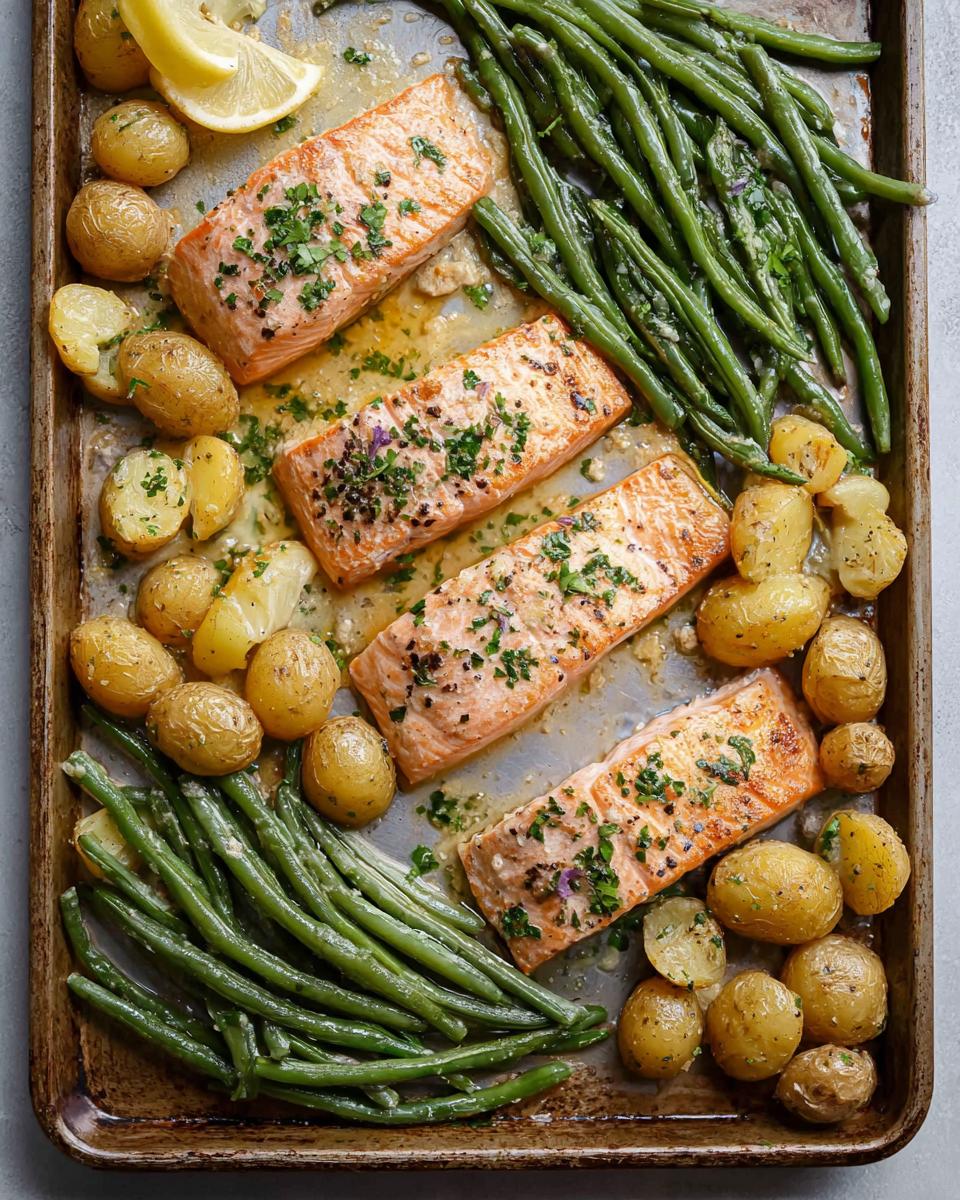 Overhead view of Sheet-Pan Salmon & Veggies (Set & Forget) with three salmon fillets, green beans, and baby potatoes on a baking sheet.