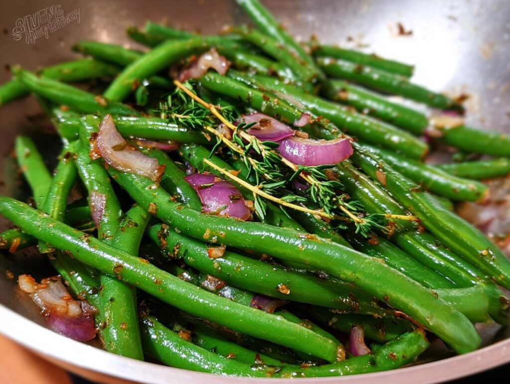 Close-up of vibrant Thanksgiving green beans cooked with red onion and fresh thyme.