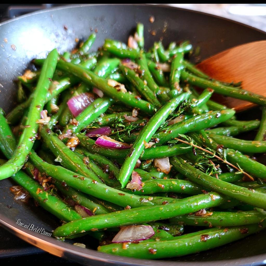 Close-up of vibrant Thanksgiving Green Beans cooking in a pan with red onion and herbs.