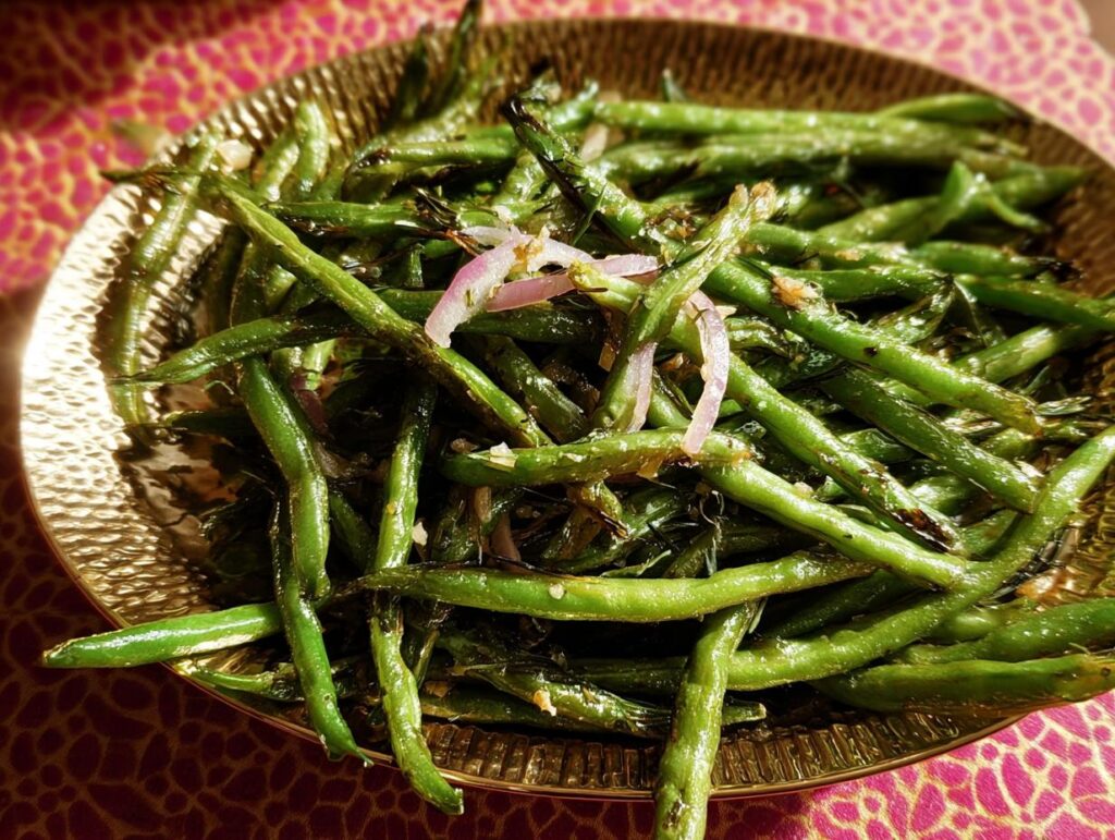 Close-up of a golden platter filled with roasted green beans, red onion slices, and herbs for the Best Thanksgiving Veggie Tray 2025.