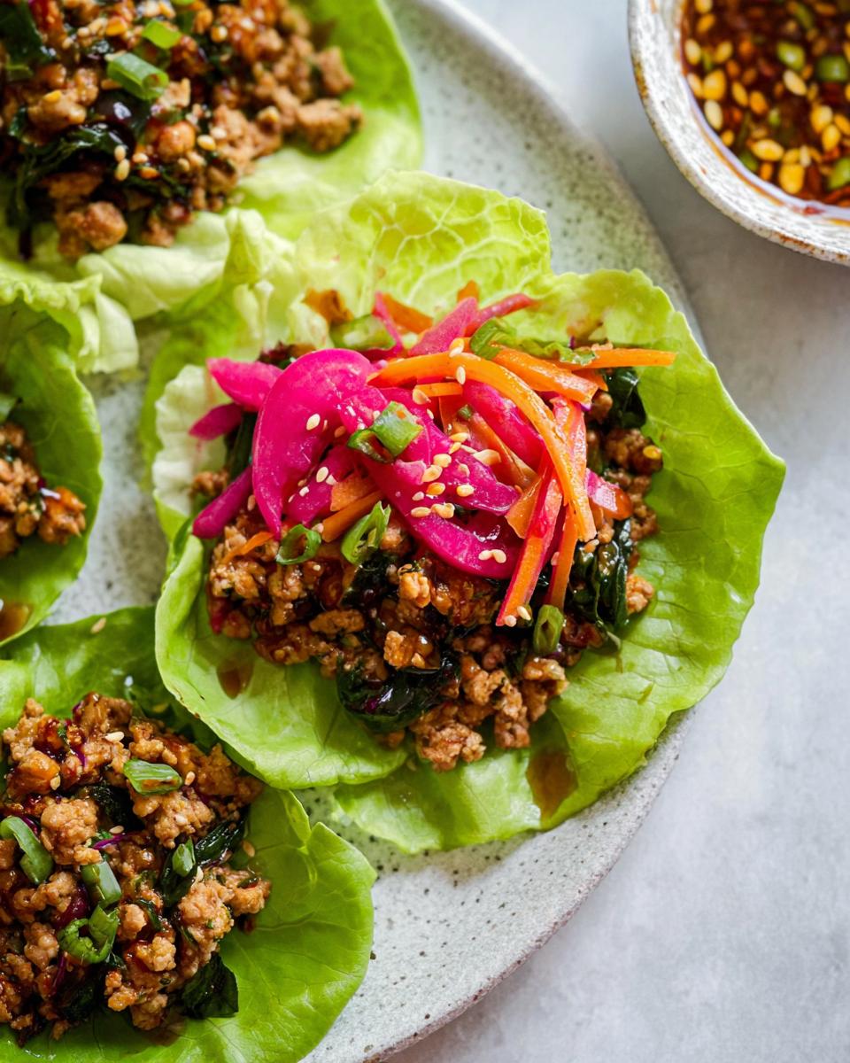 Close-up of PF-Style Turkey Lettuce Wraps filled with seasoned ground turkey and topped with pickled vegetables and sesame seeds.