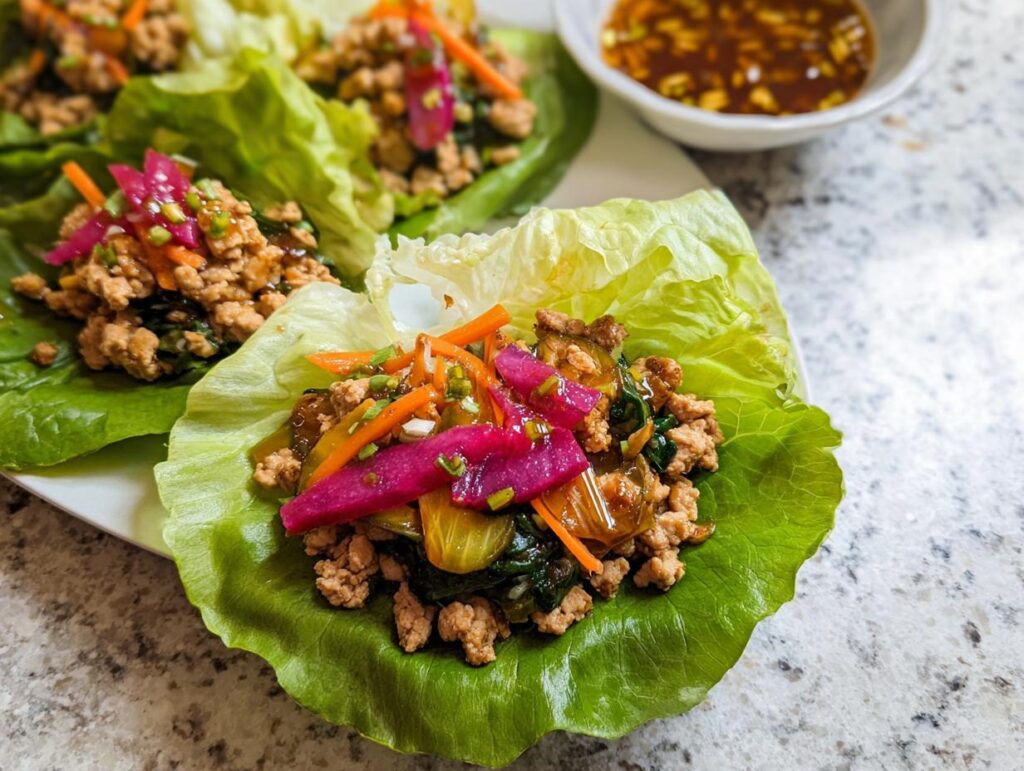 Close-up of delicious Turkey Lettuce Wraps (PF-Style) filled with seasoned ground turkey, shredded carrots, and pickled vegetables.