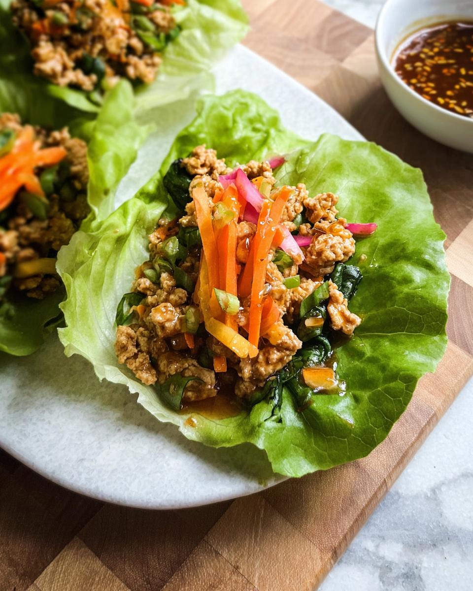 Close-up of delicious Turkey Lettuce Wraps (PF-Style) filled with seasoned ground turkey, carrots, and greens.
