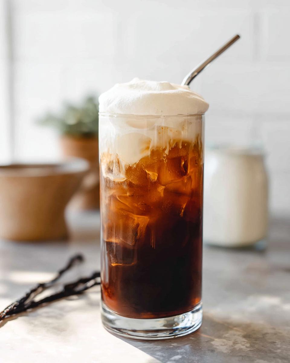 Tall glass of Vanilla Sweet Cream Cold Foam Cold Brew with ice and a metal straw.