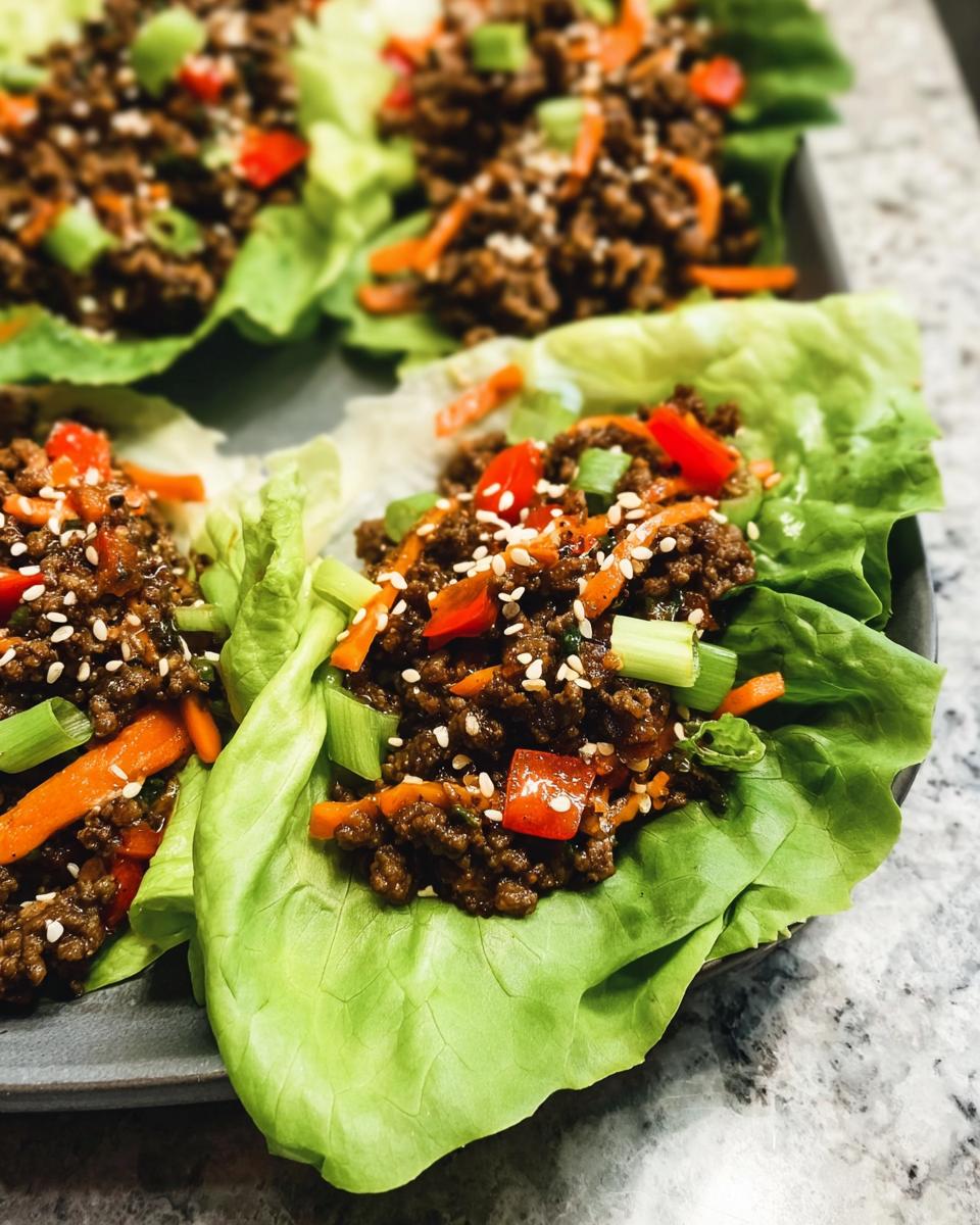Close-up of Asian Ground Beef Lettuce Wraps filled with savory meat, carrots, peppers, and sesame seeds.