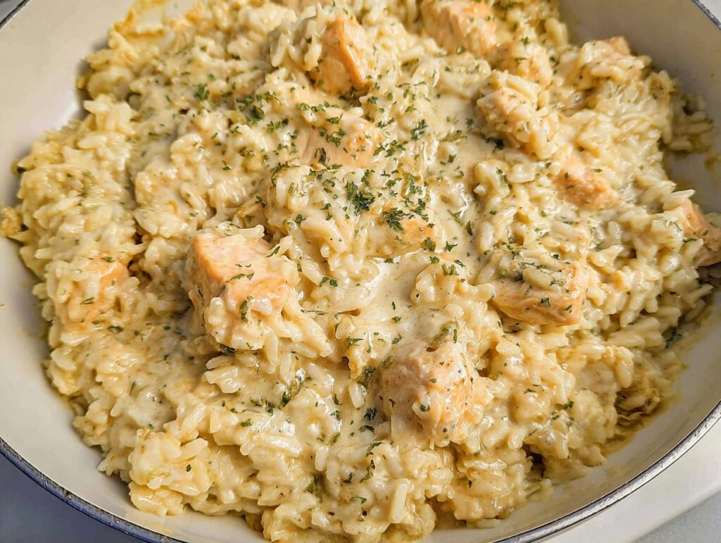 Close-up of a rich Creamy Chicken and Rice Skillet, featuring tender chicken pieces in a thick, creamy sauce with rice.