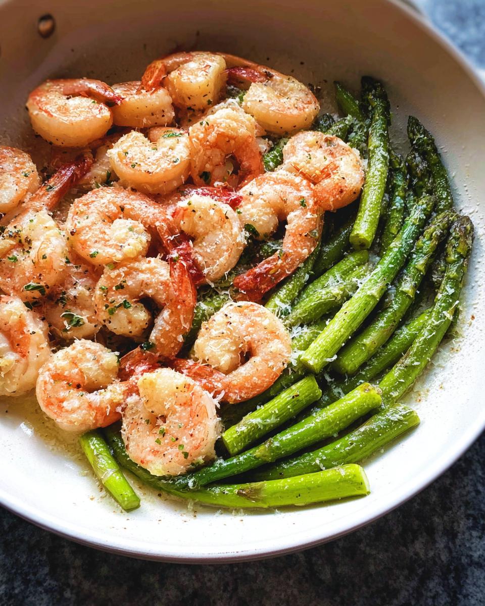 Close-up of cooked shrimp and bright green asparagus spears in a skillet, seasoned for Garlic Shrimp and Asparagus Skillet.