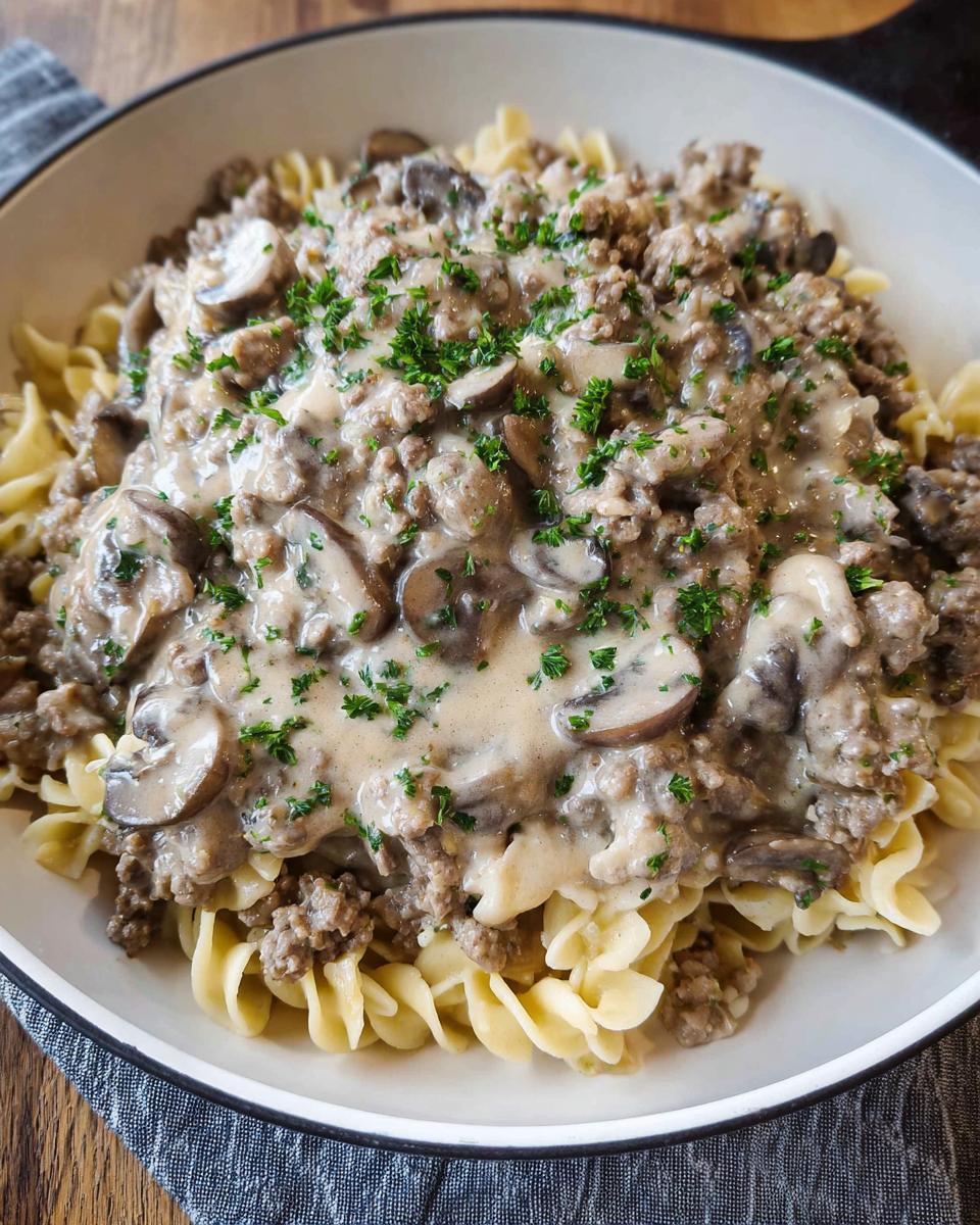 A close-up of One Pot Ground Beef Stroganoff served over egg noodles and garnished with parsley.