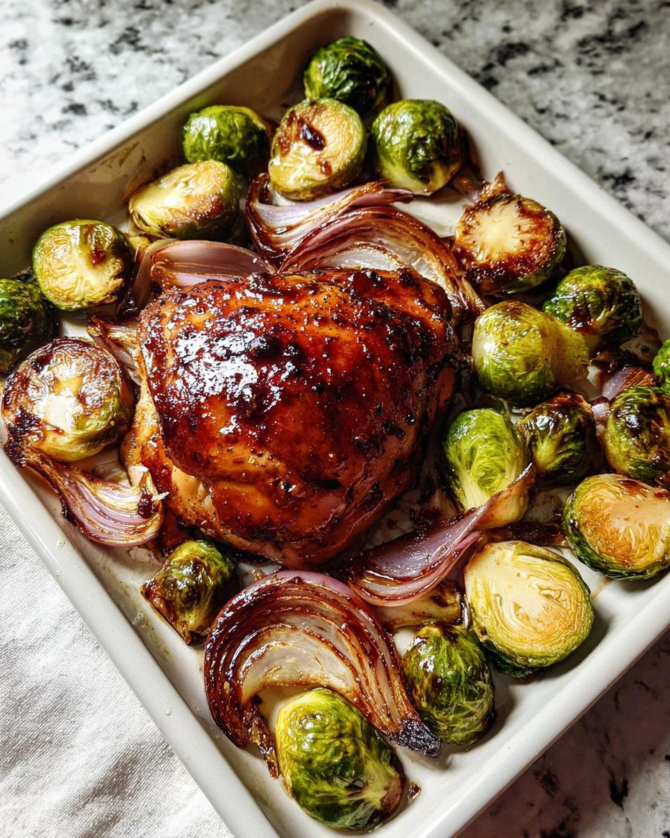 Glazed Sheet Pan Balsamic Chicken and Brussels Sprouts roasted in a white baking dish.