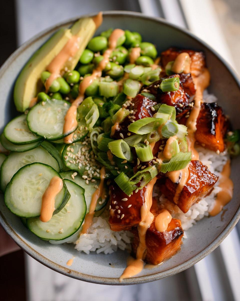 Close-up of Teriyaki Glazed Salmon Rice Bowls topped with cucumber, avocado, edamame, and spicy mayo.
