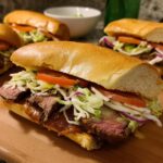 Close-up of a mouthwatering steak sandwich with lettuce, tomato, onion, and sauce on a bun.