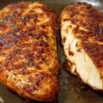 Close-up of two perfectly cooked air fryer chicken breasts, one sliced to show juicy interior.