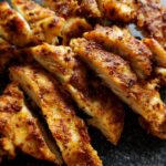 Close-up of perfectly cooked air fryer chicken recipes, sliced and seasoned with spices.