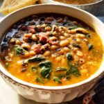 A close-up of a bowl of hearty black eyed peas soup with ham and greens, perfect for beginner soup recipes.