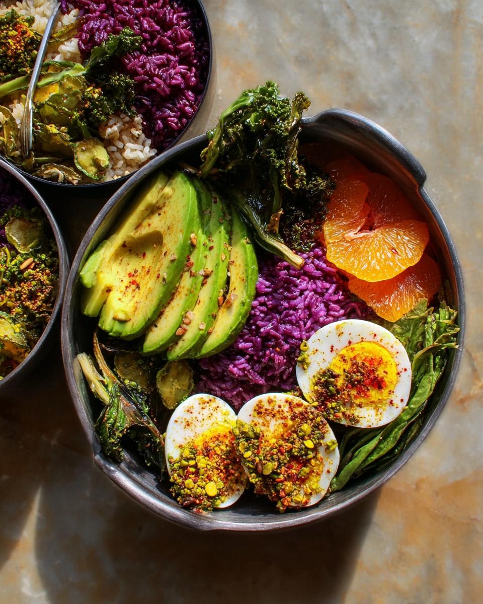 A vibrant egg bowl featuring halved hard-boiled eggs, sliced avocado, purple rice, and orange slices, part of egg recipes for beginners.