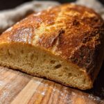 A close-up of a freshly baked loaf of bread, sliced to show its airy crumb and golden crust, perfect for healthy meals recipes.