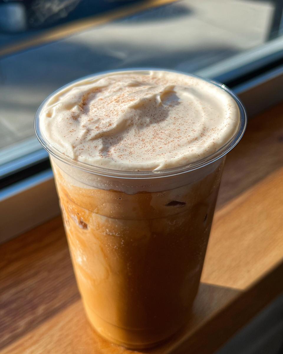A tall iced coffee drink topped with whipped cream and a sprinkle of cinnamon, perfect for restaurant-style Starbucks drinks recipes at home.