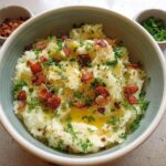 A bowl of fluffy mashed potatoes topped with crispy bacon bits, fresh parsley, and melted butter. Part of 10 Genius Mashed Potatoes Recipes.