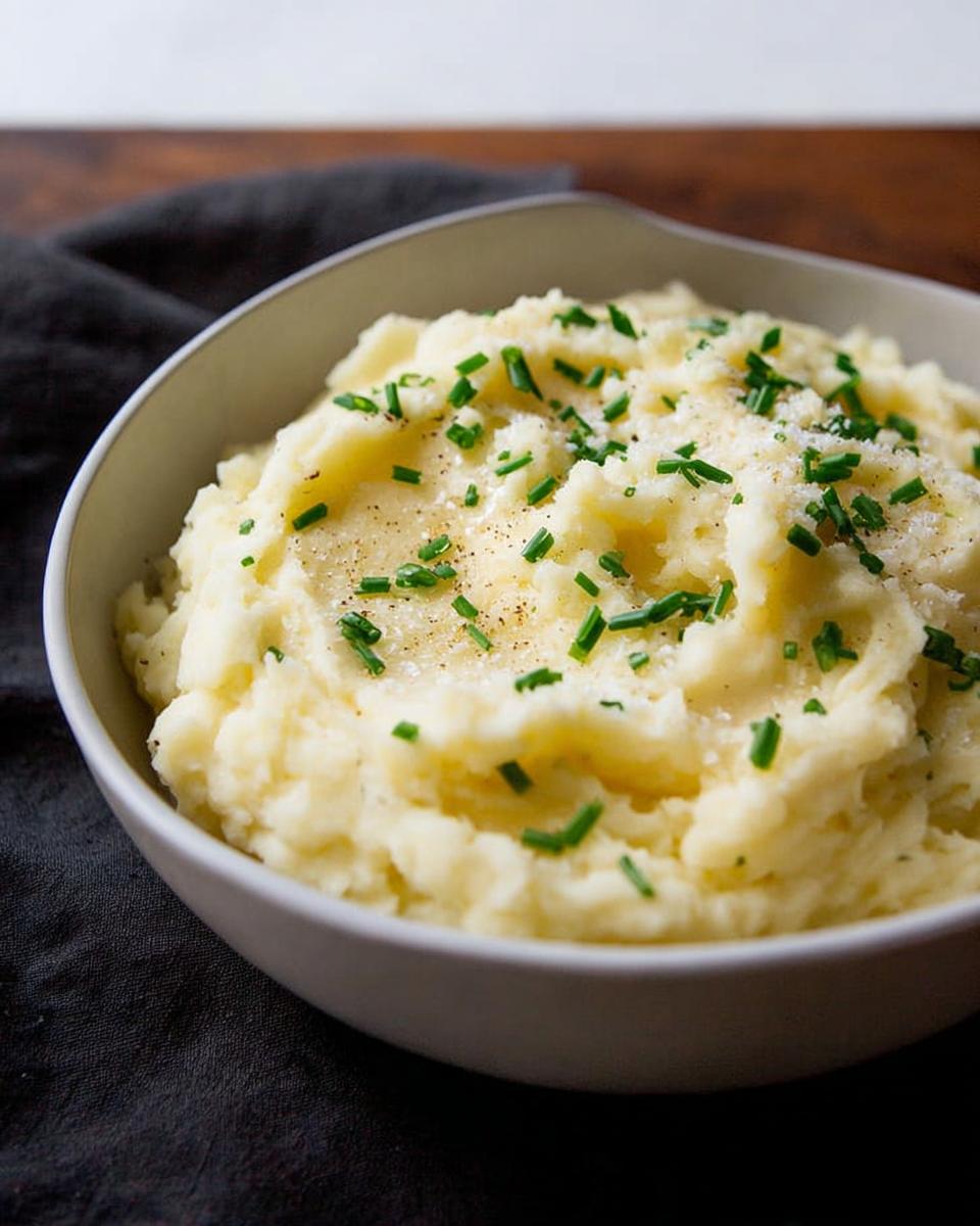 A bowl of creamy mashed potatoes topped with chives and black pepper, part of The Ultimate Mashed Potatoes Recipes Guide for Beginners.