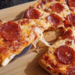 A slice of classic pepperoni pizza being lifted, showing melted cheese strings, as part of 12 Genius Pizza Night Recipes Ideas for Busy Weeknights.