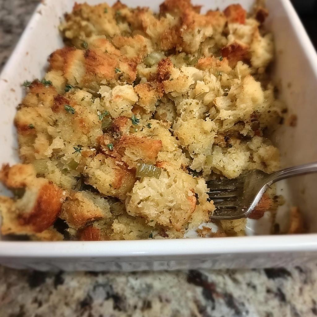 Close-up of a fork digging into a dish of homemade restaurant-style stuffing.