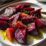 Close-up of roasted beet side dish recipe, featuring vibrant red beets cut into wedges and drizzled with a light vinaigrette and herbs.