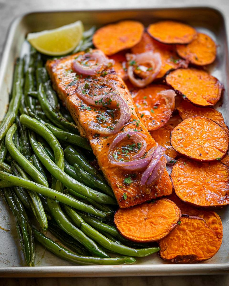 A delicious and healthy salmon meal prep with roasted sweet potatoes and green beans, topped with red onion and a lime wedge.