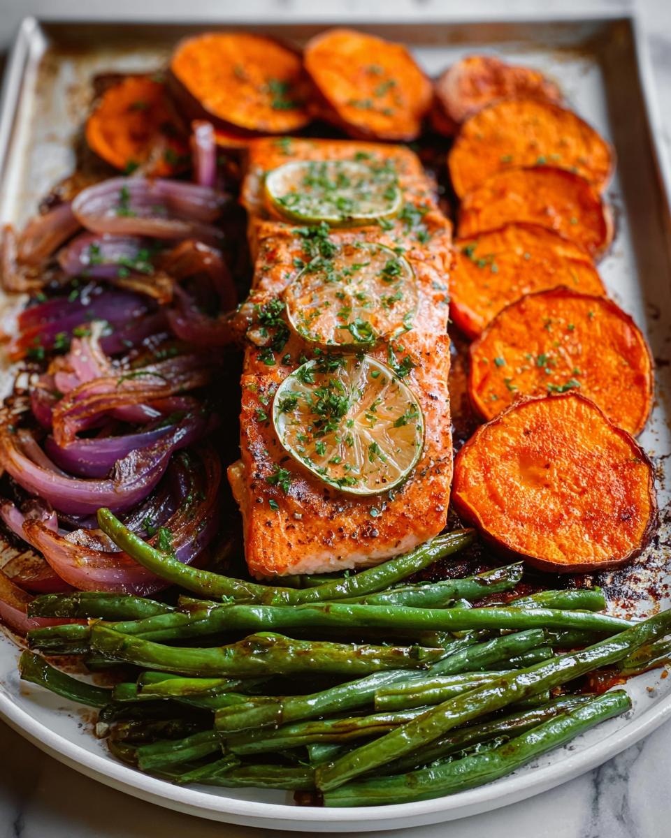 A delicious sheet pan meal with a fillet of salmon, roasted sweet potato slices, red onions, and green beans, perfect for salmon recipes meal prep.