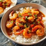 A close-up of a bowl filled with white rice and topped with succulent shrimp in a savory sauce, a popular choice for shrimp recipes.