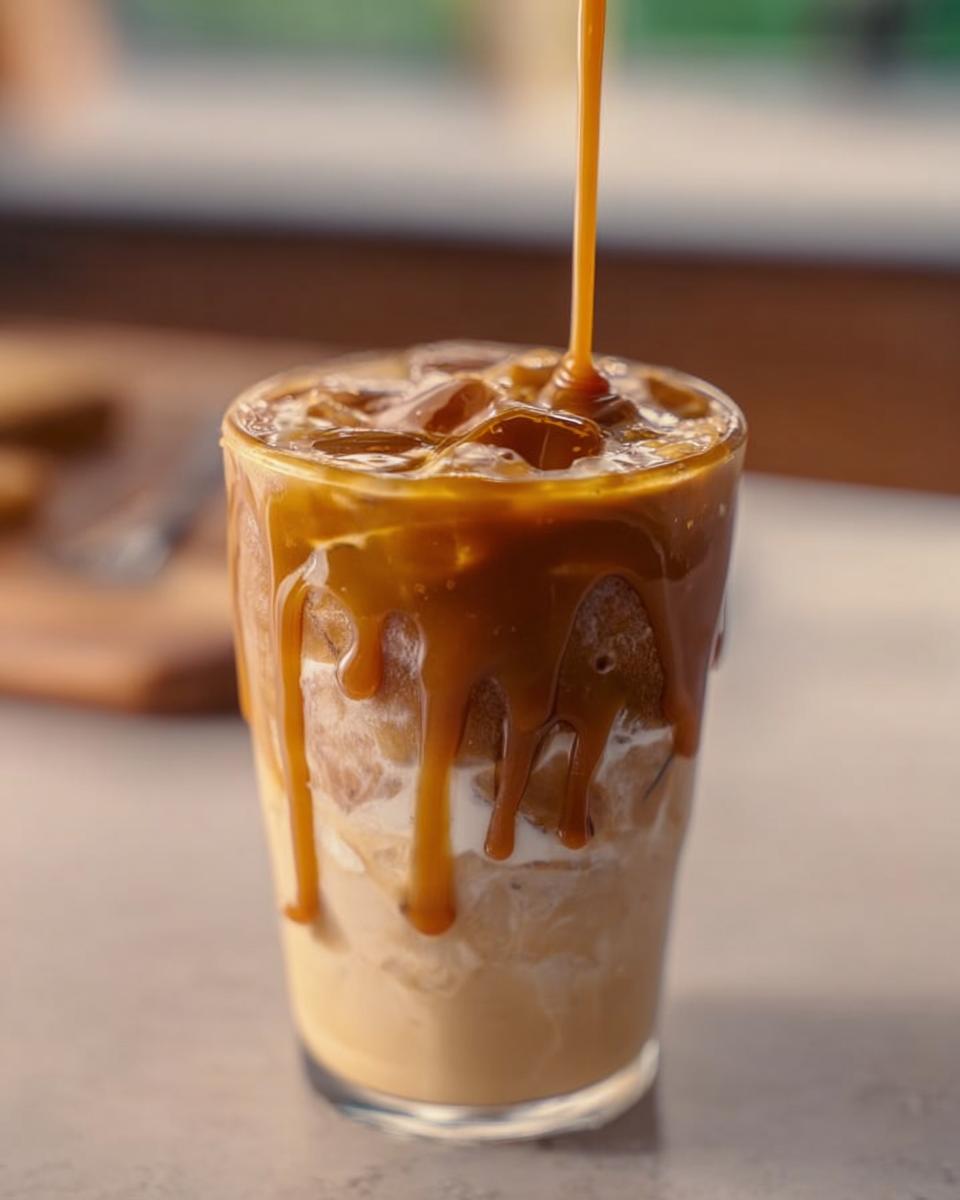 Close-up of an iced coffee with caramel sauce being drizzled on top, a popular Starbucks drinks recipe.