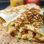 Close-up of two Cozy Cheesy Garlic Chicken Wraps, showing tender chicken and melted cheese spilling out, garnished with parsley.