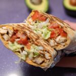 A cross-section of an Easy Chipotle Ranch Grilled Chicken Burrito, showing grilled chicken, lettuce, tomato, cheese, and sauce.