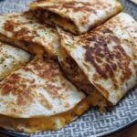 Close-up of golden-brown High-Protein Chicken Ranch Quesadilla slices, filled with melted cheese and herbs.