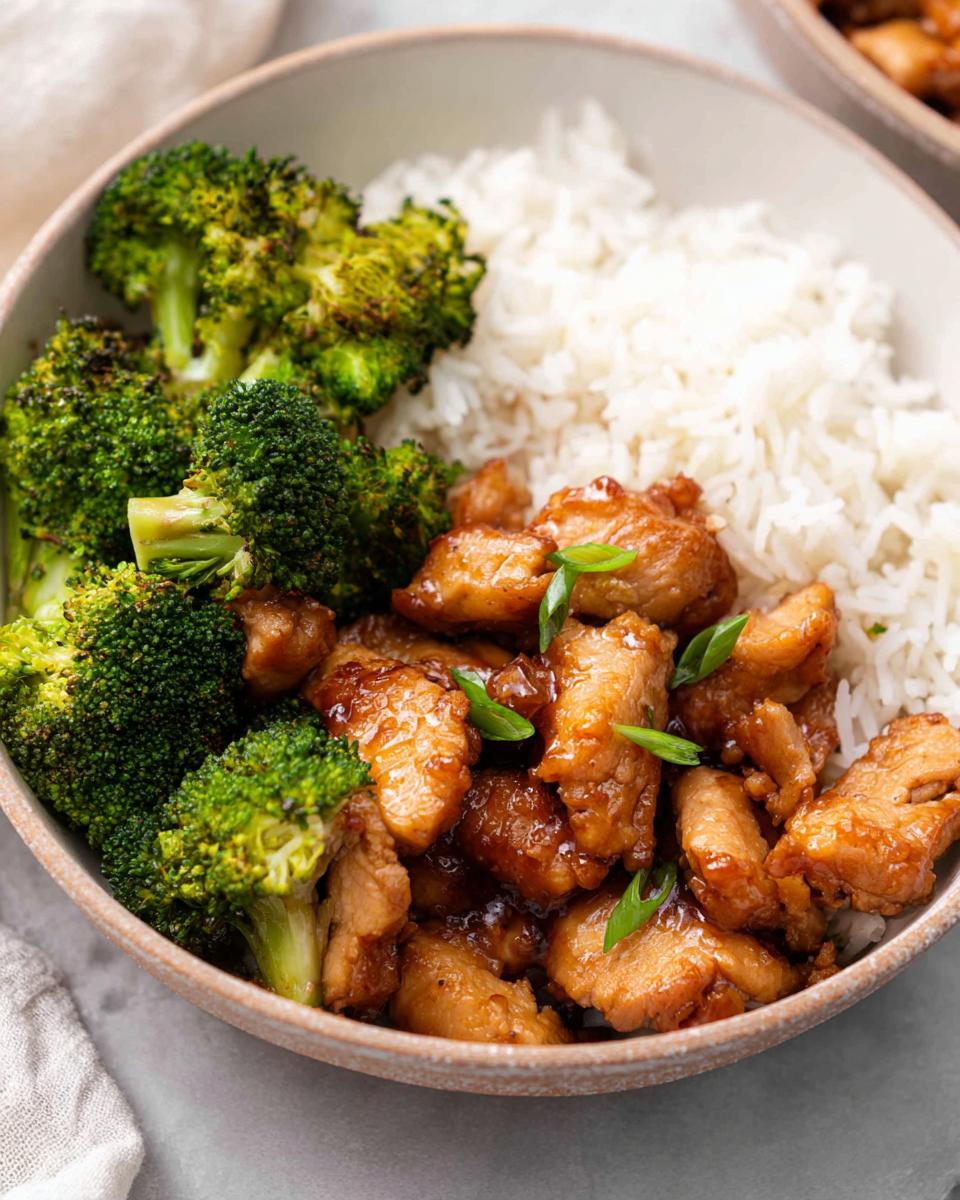 A close-up of a Honey Garlic Pork Rice Bowl with tender pork, steamed rice, and roasted broccoli.