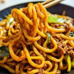 Close-up of thick, chewy udon noodles coated in a savory sauce with ground meat and vegetables in an Irresistible Yaki Udon Noodle Recipe.