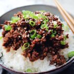 A close-up of a Korean Ground Beef Bowl, featuring savory ground beef over fluffy white rice, garnished with green onions and sesame seeds.