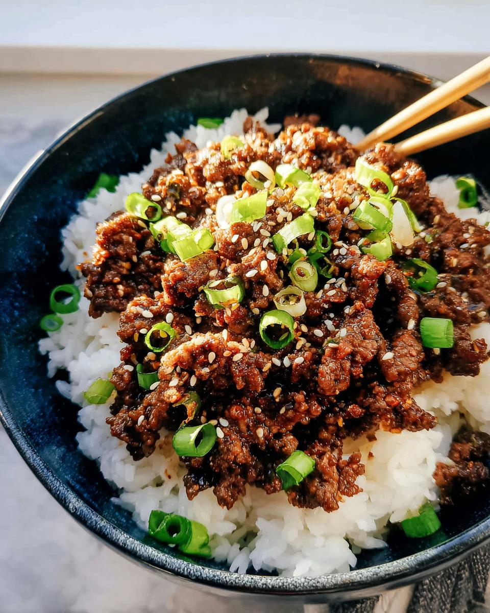 Close-up of a Korean Ground Beef Bowl, featuring seasoned ground beef over white rice, topped with sesame seeds and chopped green onions.