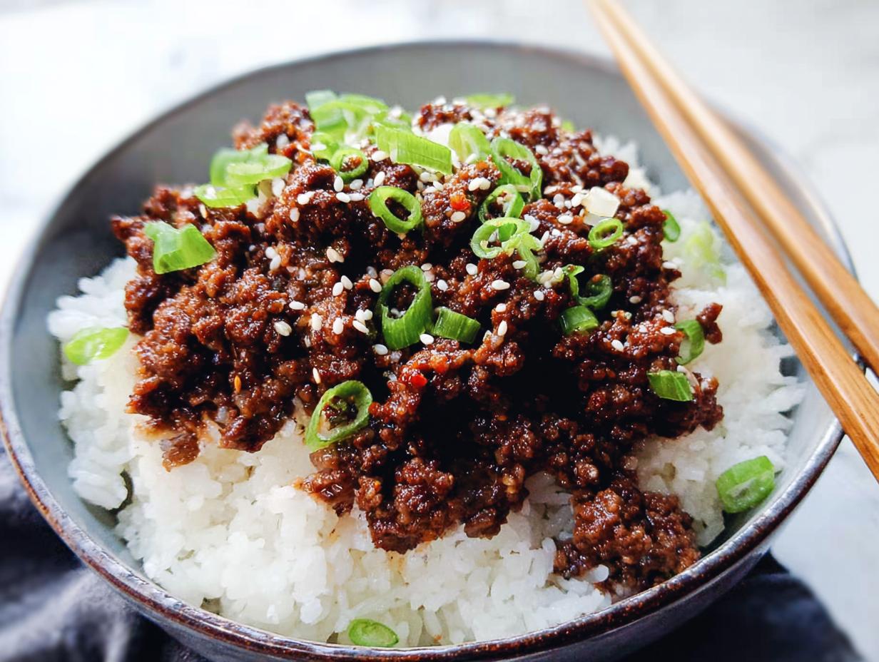 A close-up of a Korean Ground Beef Bowl, featuring savory ground beef over fluffy white rice, garnished with green onions and sesame seeds.