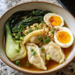 A delicious bowl of Savory Dumpling Ramen with soft-boiled eggs, bok choy, and green onions.